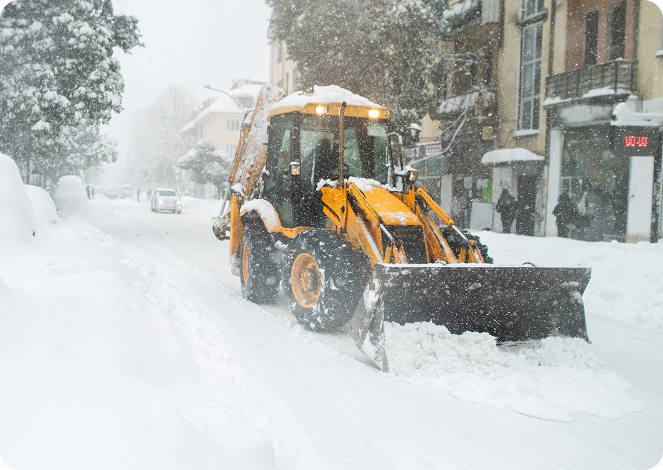 Snowplow clearing snowy urban street.